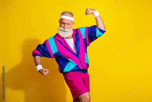 Photo of attractive funny retired sportsman retro sportswear showing biceps emtpy space isolated yellow color background photo