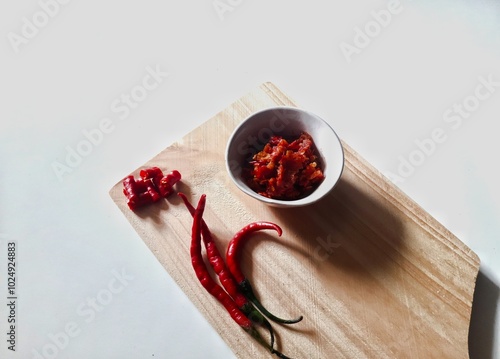 Sambal or Indonesian traditional chili sauce. Served in a small bowl on cutting board photo