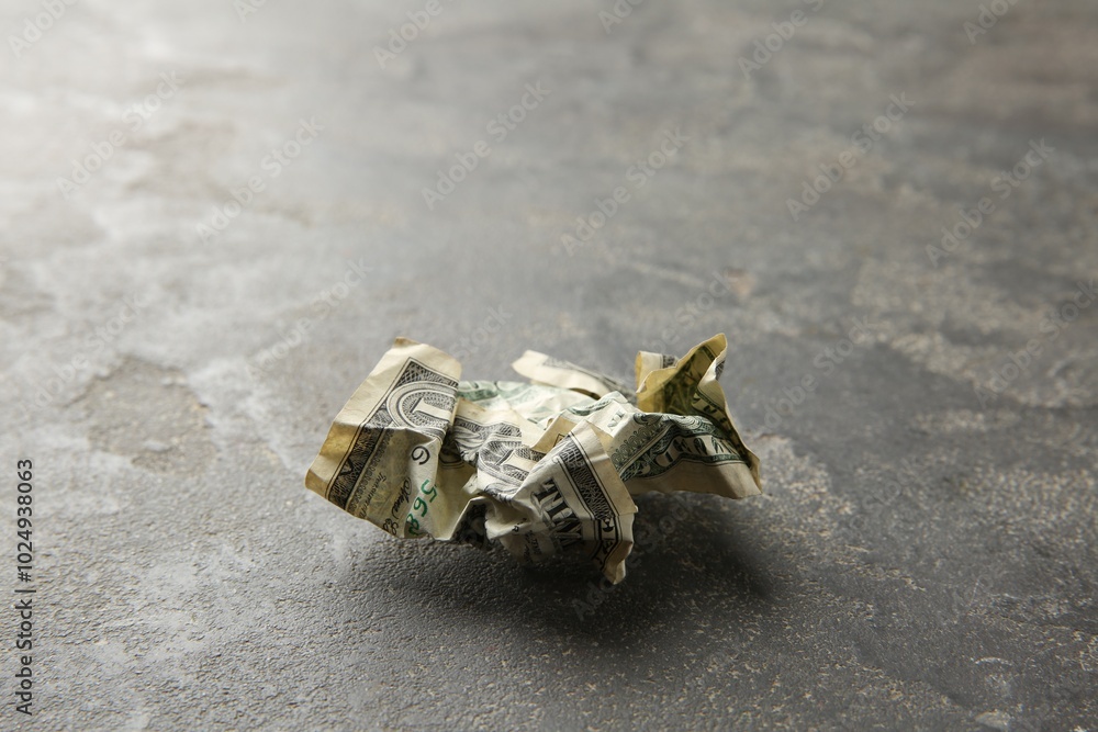 One crumpled dollar banknote on grey table, closeup One crumpled dollar banknote on grey table, closeup