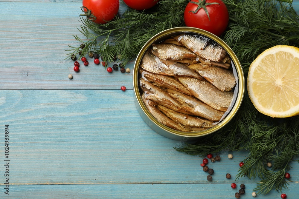 Tasty sprats in tin can served on light blue wooden table, flat lay. Space for text Tasty sprats in tin can served on light blue wooden table, flat lay. Space for text