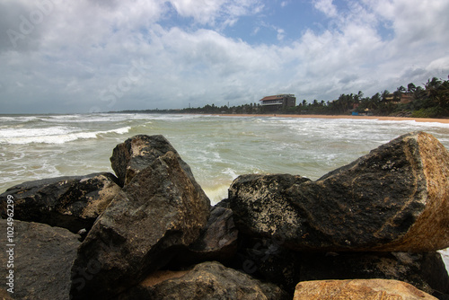 Beach, with lava rocks and vegetation, view of the sea in the evening at sunset. Landscape with clouds in Induruwa, Bentota Beach, Sri Lanka, India, Asia photo