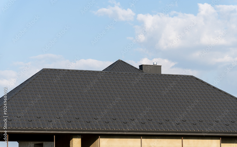 The sleek black metal roofing provides a striking contrast to the light-colored walls of the house, highlighting the modern architectural design against a bright sky The sleek black metal roofing provides a striking contrast to the light-colored walls of the house, highlighting the modern architectural design against a bright sky
