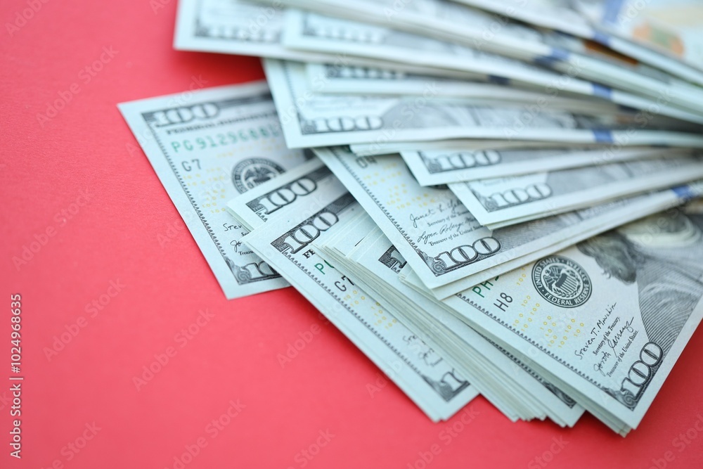 Big amount of hundred dollar bills in thick stack lies on bright red color paper background Big amount of hundred dollar bills in thick stack lies on bright red color paper background