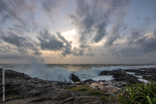 Beach, with lava rocks and vegetation, view of the sea in the evening at sunset. Landscape with clouds in Induruwa, Bentota Beach, Sri Lanka, India, Asia photo