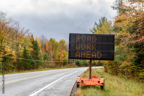 Digital road sign indicating roadworks ahead on a trailer along a forest road in the mountains on a cloudy autumn day
