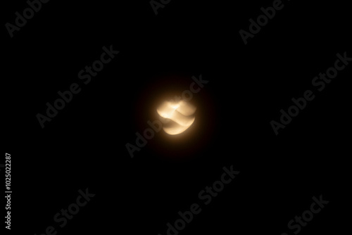 Abstract light trail of a crescent moon captured in motion with a blurred effect against a dark night sky