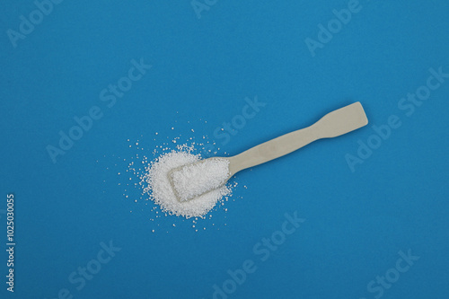 Sodium percarbonate powder or sodium carbonate peroxide on ceramic spatula on blue surface, top view. It is abbreviated as SPC. Chemical substance used in eco-friendly bleaches with active oxygen. photo