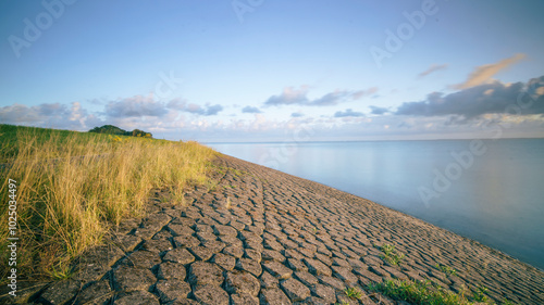 Foto Massive dike along the waterfront of the Dutch coastline that curves away in a b
