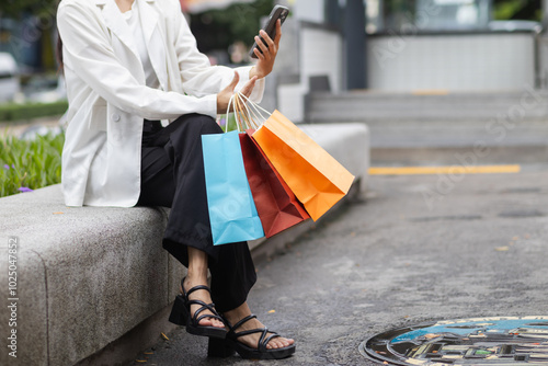 Businesswoman holding shopping paper bags in a shopping mall and is happy after shopping for her needs during the festival. Paper bags containing a lot of products are in hands of Asian businesswoman.