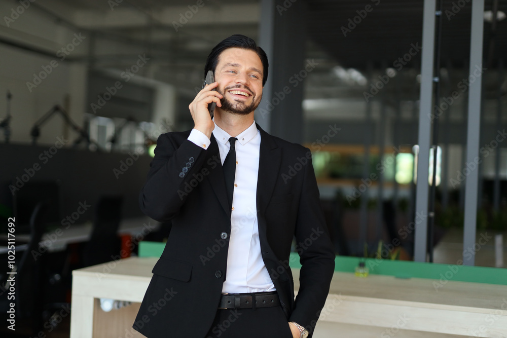 A man in a suit is talking on his cell phone. He is smiling and he is in a good mood A man in a suit is talking on his cell phone. He is smiling and he is in a good mood