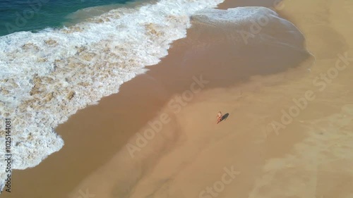 Wallpaper Mural Aerial drone footage of a woman walking a white sand beach in front of crashing waves on a clear summer day Torontodigital.ca