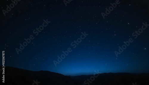 Starry Night Sky with Blue Horizon over Silhouetted Mountains