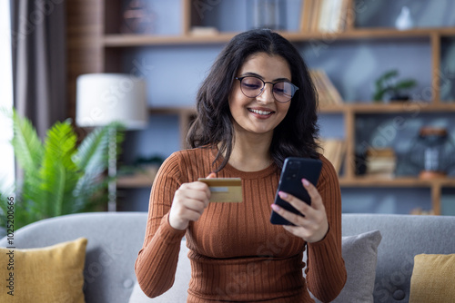 Canvas Print Close-up photo of a young smiling Muslim girl at home, sitting on the sofa, hold