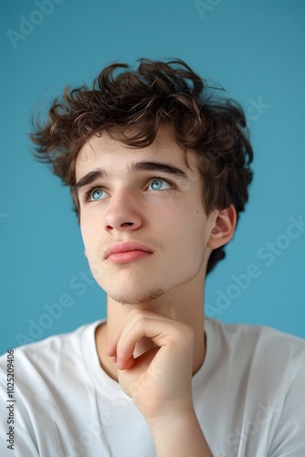 Pensive young man with a curious expression on a blue background