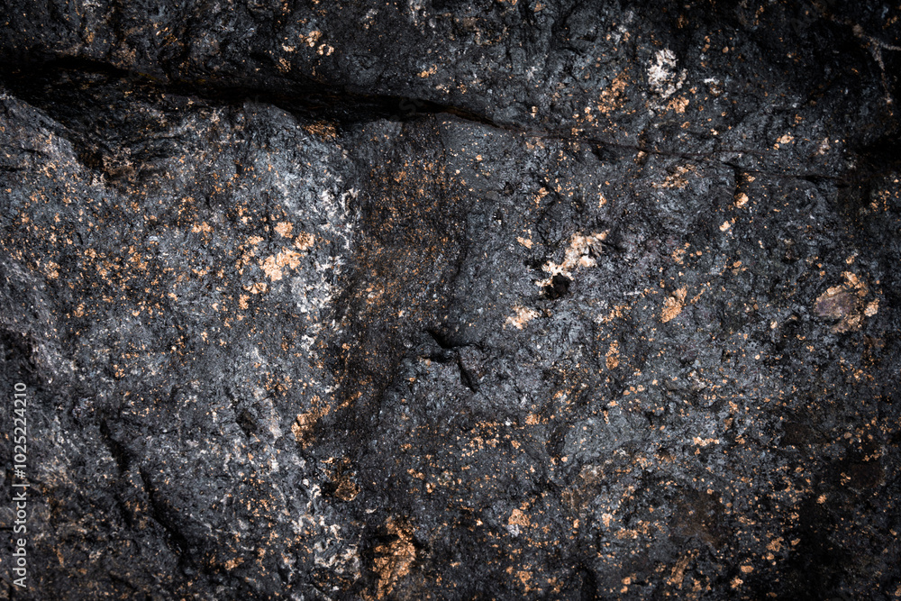 Dark textured stone surface with golden flecks. The stone is cracked, adding a sense of natural ruggedness and strength. Dark textured stone surface with golden flecks. The stone is cracked, adding a sense of natural ruggedness and strength.