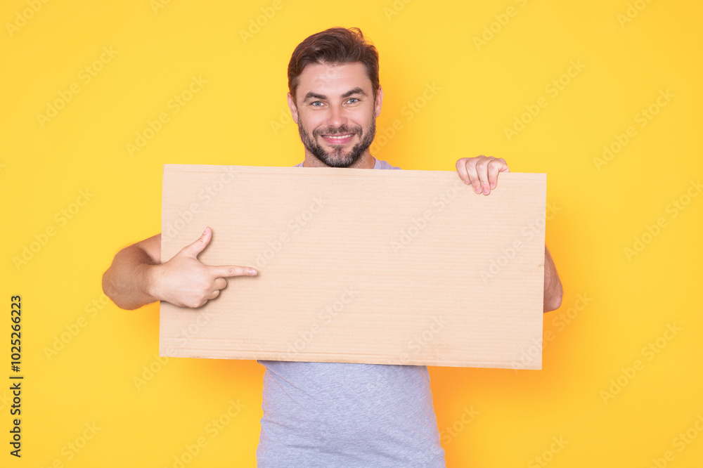 Guy with blank banner ad, isolated on studio background. Man holding empty blank poster showing placard pointing finger and gesturing index finger on board. Male presenting signboard or banner. Guy with blank banner ad, isolated on studio background. Man holding empty blank poster showing placard pointing finger and gesturing index finger on board. Male presenting signboard or banner.
