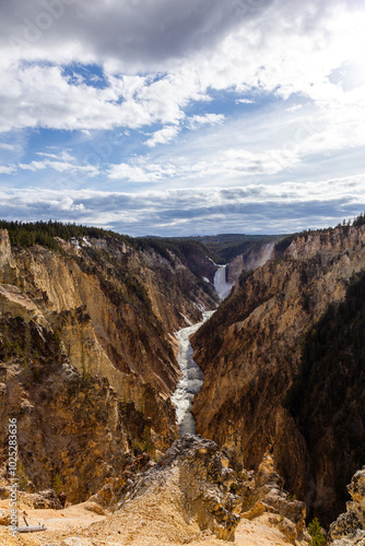 Majestic View of the Grand Canyon of the Yellowstone in Wyoming, USA with Towering Waterfalls and Rugged Cliffs Under a Dramatic Cloudy Sky