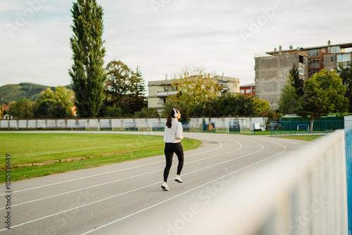 Young caucasian woman running or jogging on the stadium track