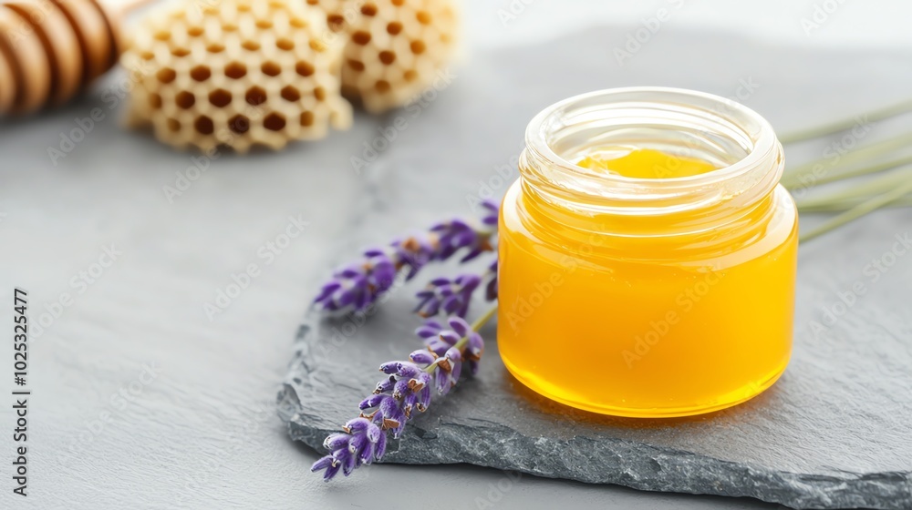 Jar of golden honey with lavender flowers on gray slate surface. Jar of golden honey with lavender flowers on gray slate surface.