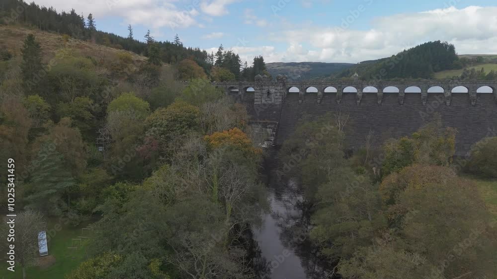 Camera panning over river and dam surrounded by autumnal forest Camera panning over river and dam surrounded by autumnal forest