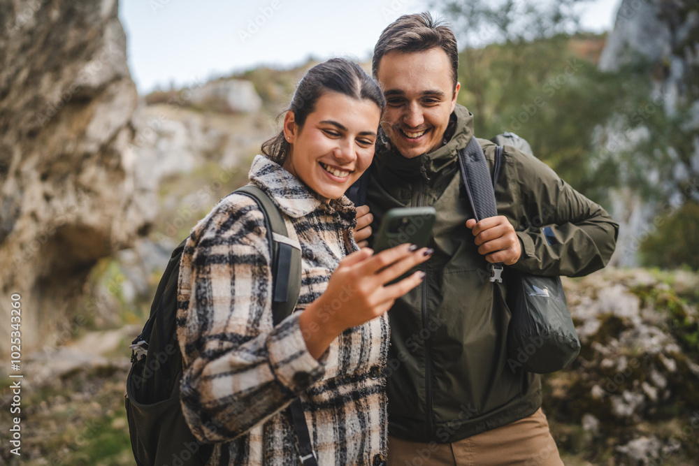 couple take a break from hiking and use mobile phone having fun couple take a break from hiking and use mobile phone having fun