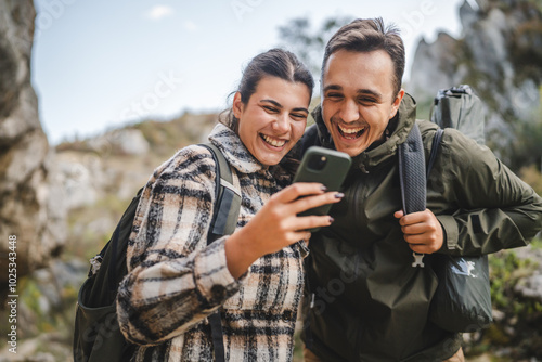 couple take a break from hiking and use mobile phone having fun