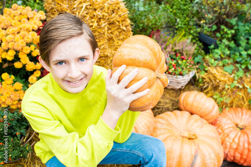 Portrait of smiling 12 year old boy with pumpkin at autumn festival photo