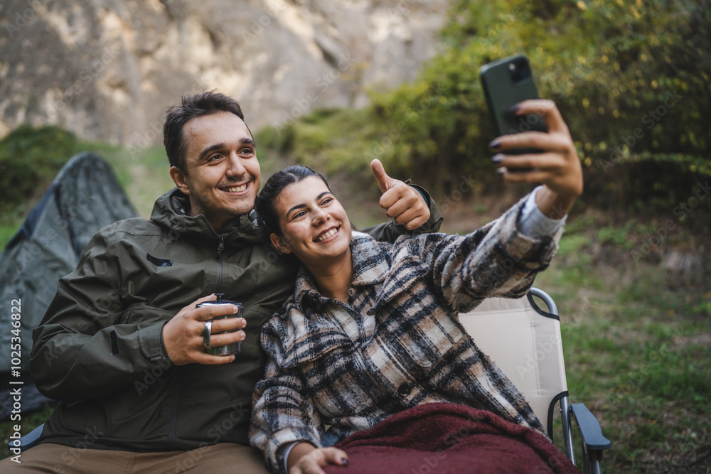 Fototapeta premium happy couple campers take a self portrait or video call in front tent