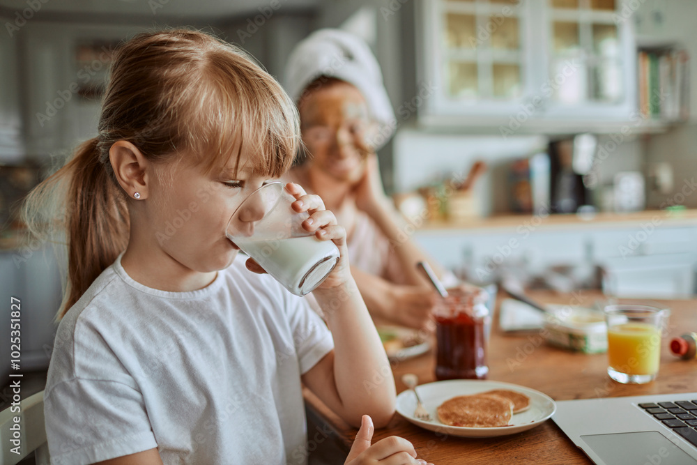 Mother and daughter laughing while having breakfast together at home Mother and daughter laughing while having breakfast together at home