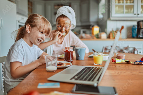 Mother and daughter laughing while having breakfast together at home