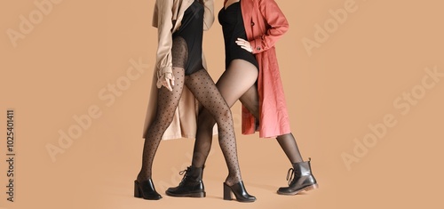 Fashionable young women in tights on beige background photo