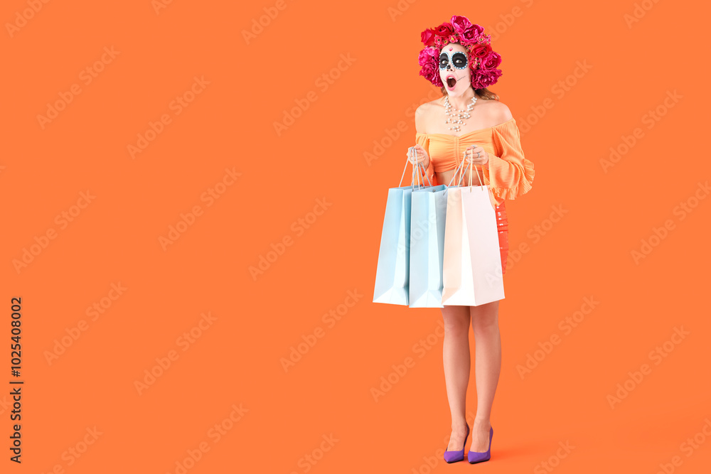 Young woman with painted skull and shopping bags on orange background. Mexico's Day of the Dead (El Dia de Muertos) celebration Young woman with painted skull and shopping bags on orange background. Mexico's Day of the Dead (El Dia de Muertos) celebration