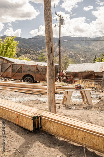 Construction site with lumber, old trailer, and mountains in background