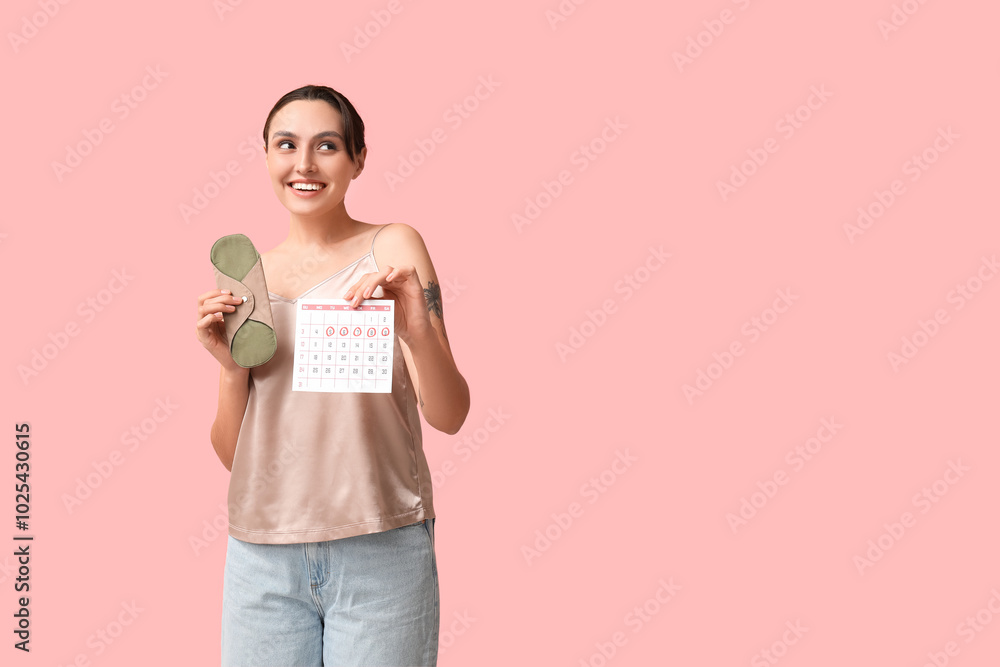 Beautiful young woman holding reusable pad and calendar with marked days of menstruation on pink background Beautiful young woman holding reusable pad and calendar with marked days of menstruation on pink background
