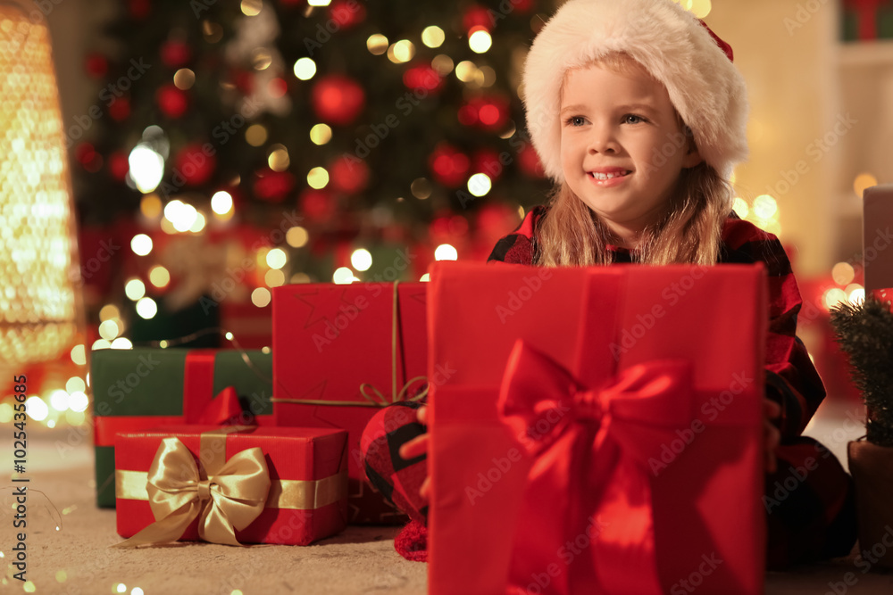 Cute little girl in Santa hat with Christmas gifts at home Cute little girl in Santa hat with Christmas gifts at home