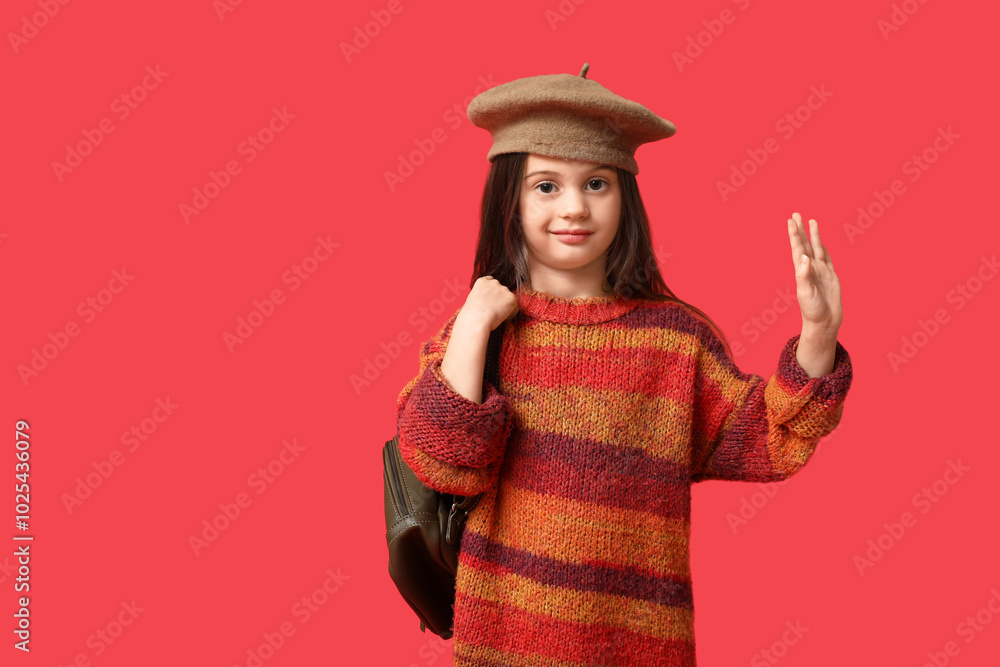 Cute little girl in stylish clothes with backpack waving hand on red background Cute little girl in stylish clothes with backpack waving hand on red background