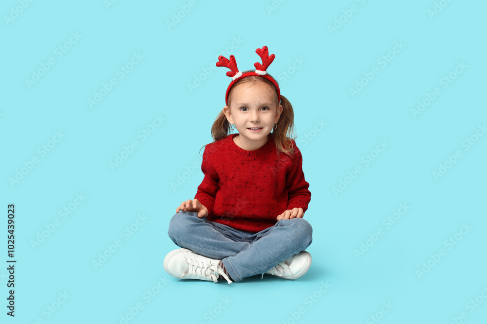 Happy little girl in reindeer horns on blue background Happy little girl in reindeer horns on blue background