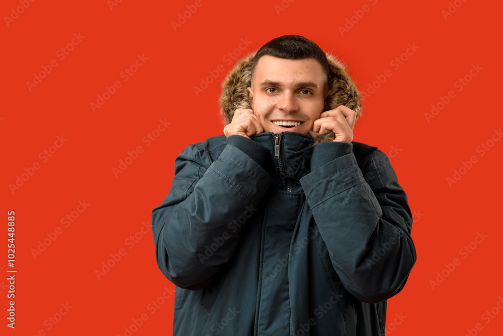 Young man in stylish puffer jacket on red background Young man in stylish puffer jacket on red background