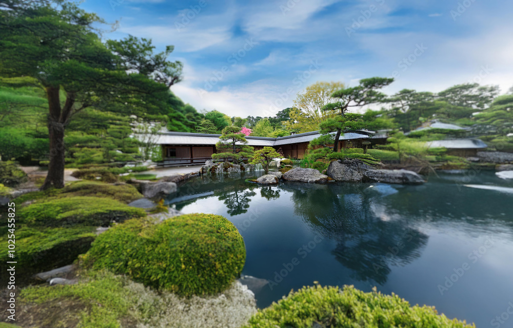 Serene pond nestled in a Japanese garden with traditional structures, lush foliage, and a clear blue sky. Serene pond nestled in a Japanese garden with traditional structures, lush foliage, and a clear blue sky.