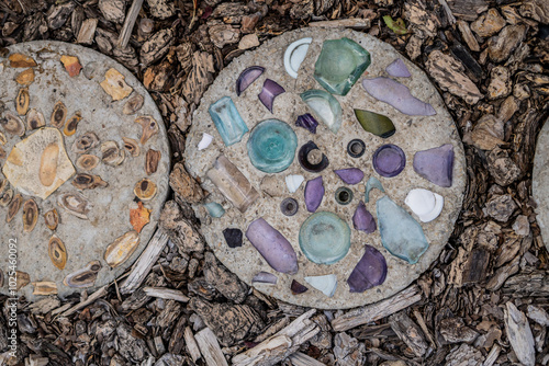 Concrete stepping stones decorated with colorful glass and stones on bark mulch ground