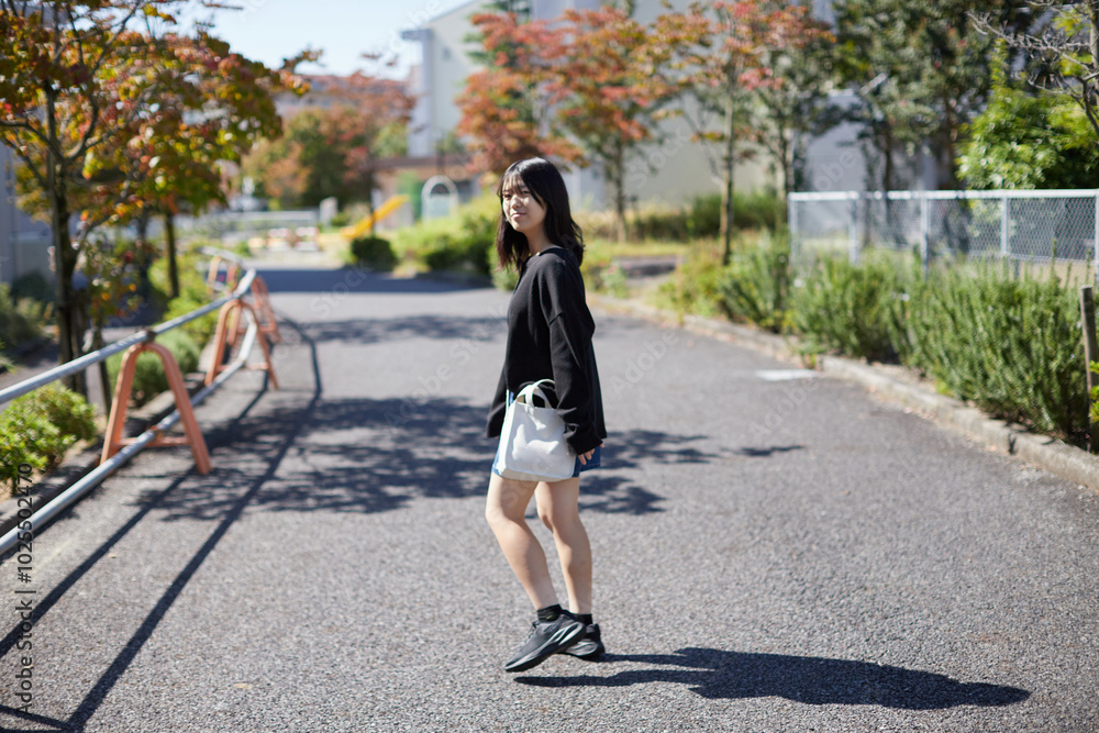 Fototapeta premium 秋の団地の敷地で歩く一人の高校生の姿
