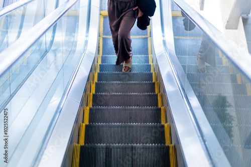 Person Walking Up Modern Escalator