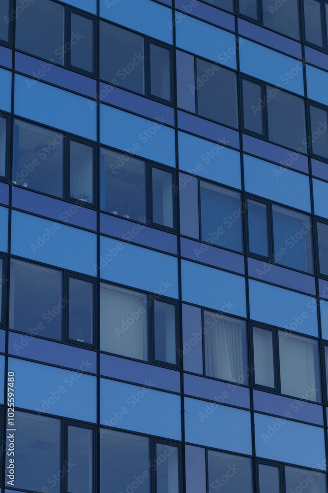 A close-up view of a modern building facade featuring a geometric pattern of blue panels with rectangular windows. 