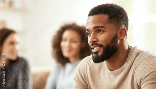 A thoughtful man engaging in conversation with friends in a cozy indoor setting.