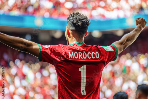 Crowd of Moroccan Supporters in Red Jerseys. A vibrant, emotional photo of a crowd of football fans cheering, with one male fan in focus, celebrating Morocco’s success in a packed stadium.

