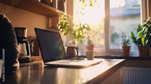 Laptop and Coffee Maker on a Kitchen Counter with Sunlight Streaming Through a Window