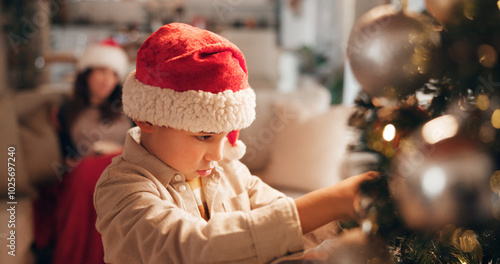 Christmas, bonding and child with ornaments, tree and decorations for holiday, hat and celebration. House, mom and boy in festive, together and season for family, relax and people in living room