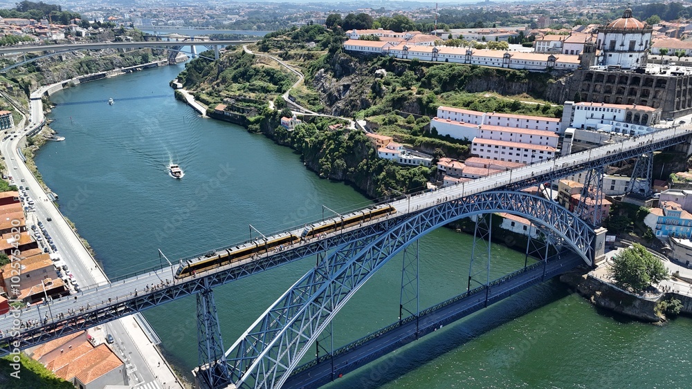 Naklejka premium Drone view of The Metro do Porto going across the iconic Luis I Bridge, connecting Porto’s historic center with Vila Nova de Gaia