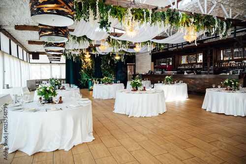 Luxurious restaurant. Luxurious interior, white tables, serving dishes and glasses for guests. Green decor photo