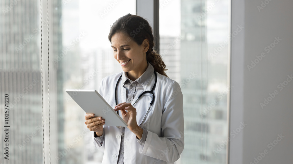 Smiling 30 years old female doctor oncologist read good labs results received by email on pad. Happy young woman medic enjoy easy access to online documents electronic patient records in medical app Smiling 30 years old female doctor oncologist read good labs results received by email on pad. Happy young woman medic enjoy easy access to online documents electronic patient records in medical app